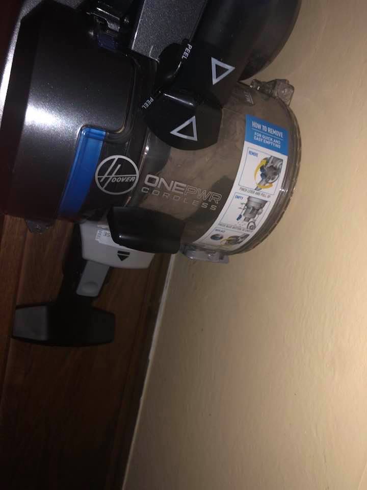Using the Hoover to dust the wall behind the fridge